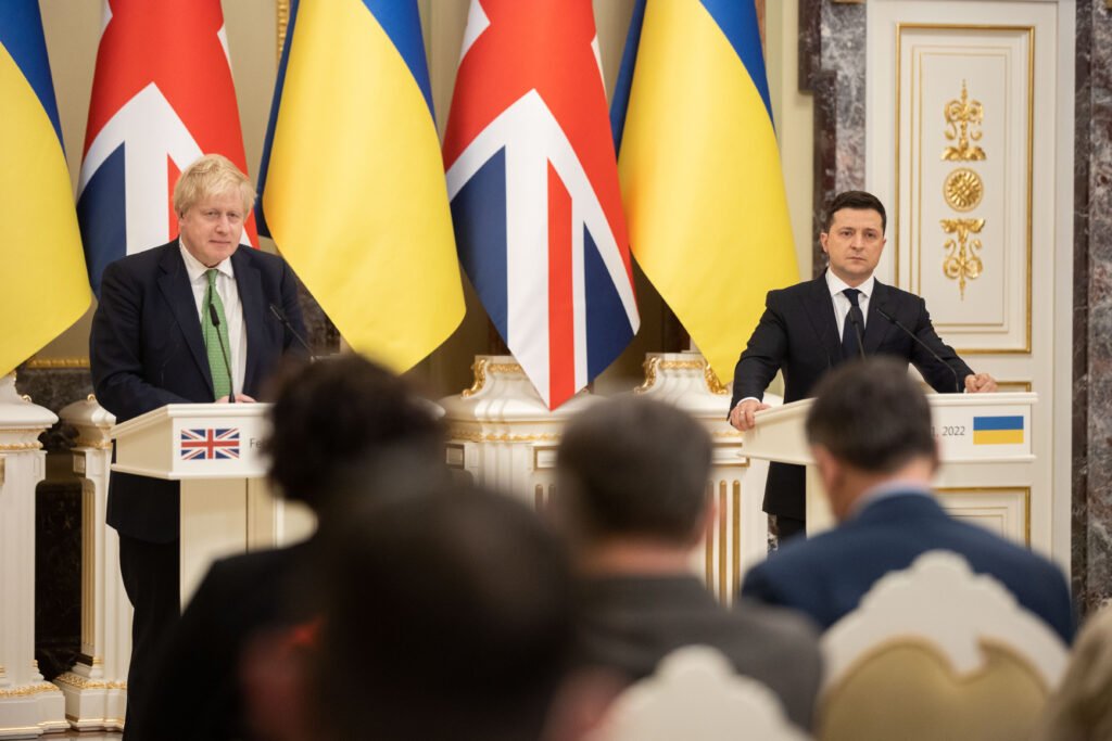 two men standing at podiums with flags in front of them